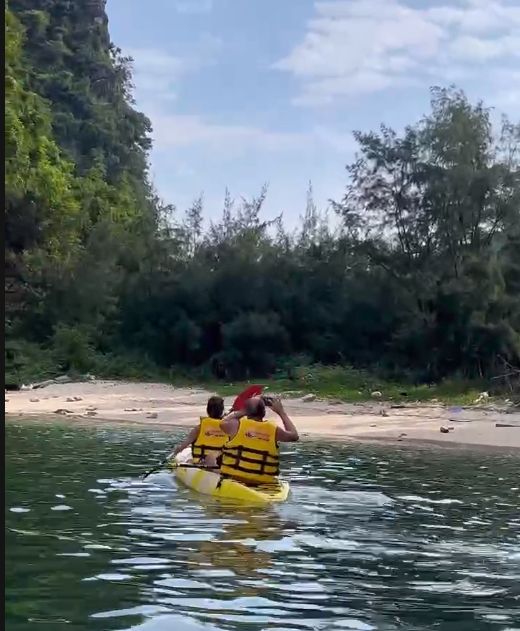 Two guests paddling a kayak along the shoreline